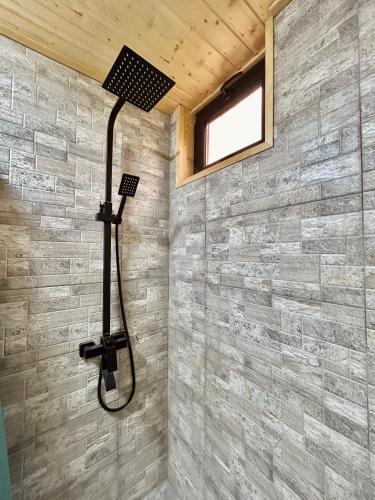 a shower in a bathroom with a stone wall at Cottage GORDA Kazbegi in Akhalts'ikhe