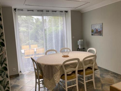 une salle à manger avec une table et des chaises et une fenêtre dans l'établissement Maison proche mer, à Agon-Coutainville