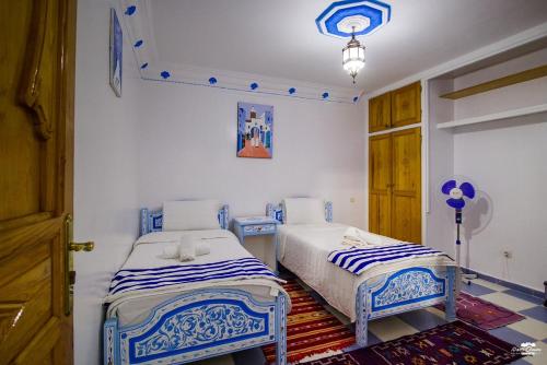 two beds in a room with blue and white at Casa Voyager 'secret garden terrace' in Chefchaouene