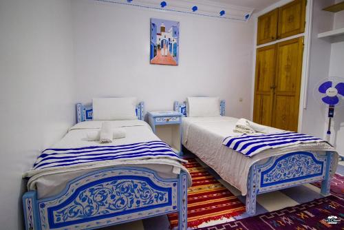 two beds in a room with blue and white at Casa Voyager 'secret garden terrace' in Chefchaouene
