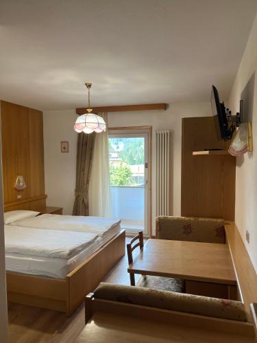 a bedroom with a large bed and a window at Dolomiten Hotel Irma in Canazei