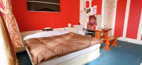 a bedroom with a bed with red walls and a desk at Hotel Sunset (Adult Only) in Choshi
