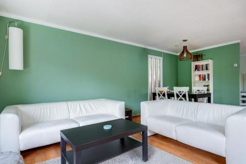 a living room with a white couch and a green wall at Rustig gelegen Vakantiehuisje in het bos - Putten in Putten