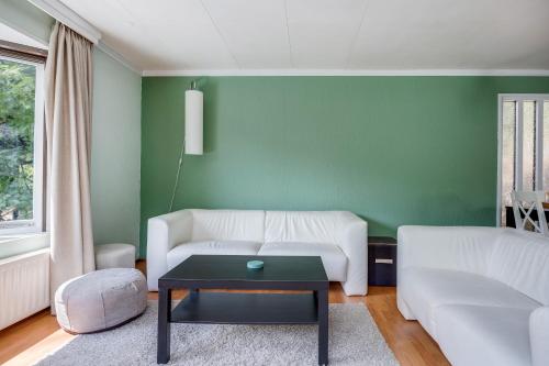 a living room with a white couch and a green wall at Rustig gelegen Vakantiehuisje in het bos - Putten in Putten