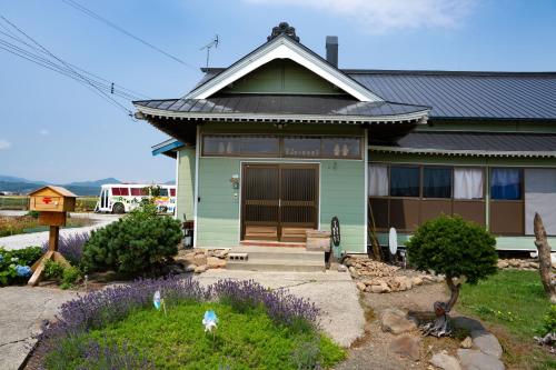a green house with a black roof at スキー場まで15分ー最大10人ーお餅つきー流しそうめんー花火ー五右衛門風呂ー心と身体が元気になる古民家民泊ーオモテナシロッジ悠遊 in Nakafurano