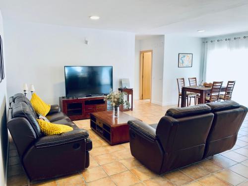 a living room with two leather couches and a flat screen tv at Hauzify I Casa Gaditana in Santa Cristina d'Aro