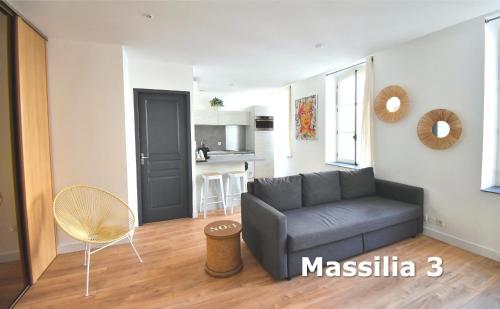 a living room with a gray couch and a kitchen at Les Appartements du Vieux Port in Marseille