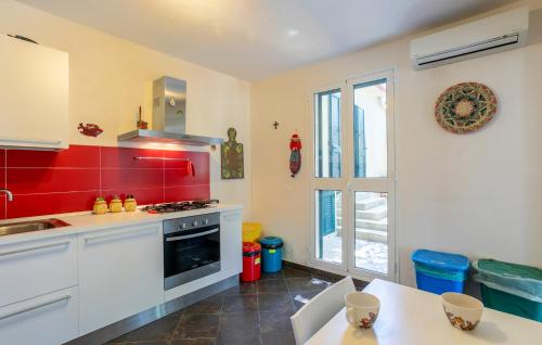 a kitchen with white cabinets and a red wall at 4 Bedroom Nice Home In Ragusa in Ragusa