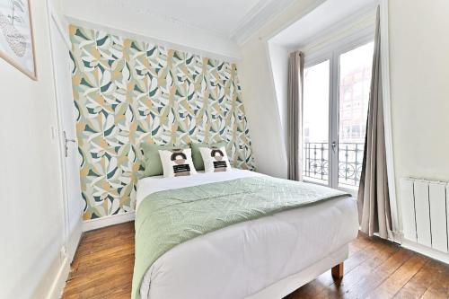 une chambre avec un lit et une grande fenêtre dans l'établissement Appartement cosy face de Paris Montparnasse, à Paris