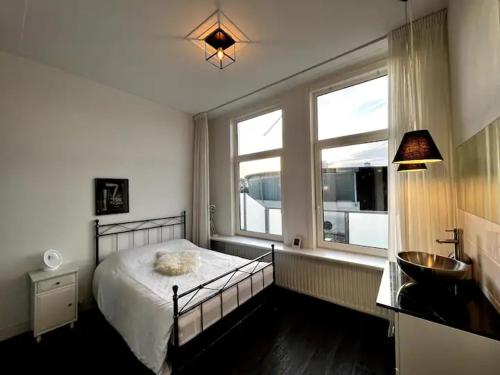 1 dormitorio con 1 cama, lavamanos y 2 ventanas en Herenhuis aan Zeezicht, en Vlissingen