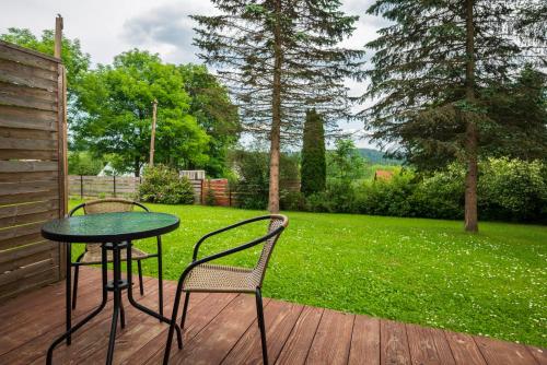a table and chairs on a deck with a lawn at AgroOsada u Beatki - Sauna & Jacuzzi in Lutowiska