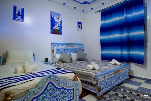 two beds in a room with blue and white at Casa Voyager 'secret garden terrace' in Chefchaouene