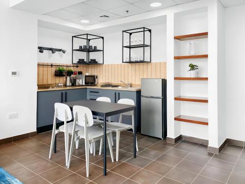 a kitchen with a black table and white chairs at Emirates Sports Hotel, Dubai Sports City in Dubai