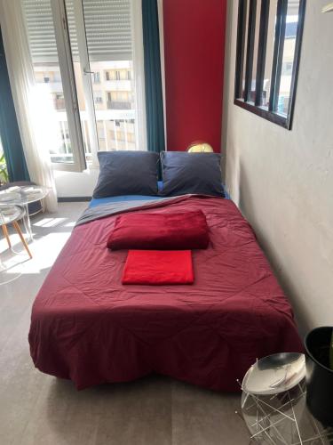 Cette chambre comprend un grand lit et une couverture rouge. dans l'établissement Escale urbaine studio Rennes, à Rennes