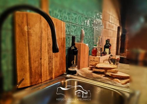 a kitchen sink with bread and wine bottles on the counter at Refúgio dos Capelinhos - Villa e Suites in Norte Pequeno