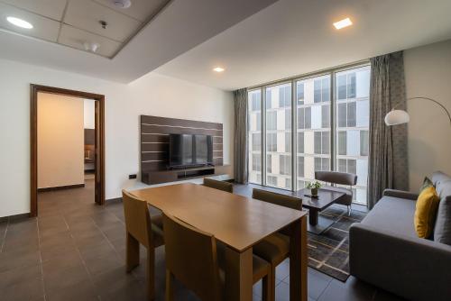 a living room with a table and a couch and a television at Emirates Sports Hotel, Dubai Sports City in Dubai