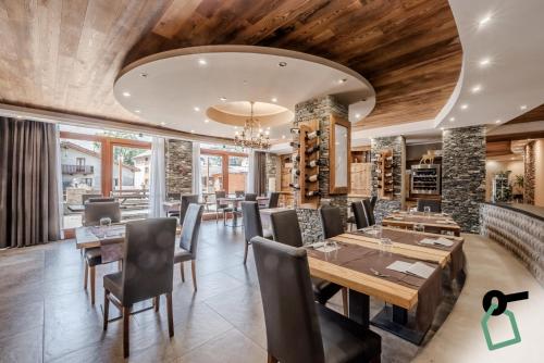 a restaurant with wooden ceilings and tables and chairs at Hotiday Room Collection - Sauze Assietta in Sauze dʼOulx