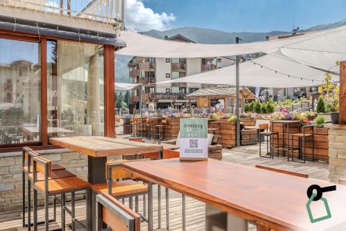 a restaurant with tables and chairs and a patio at Hotiday Room Collection - Sauze Assietta in Sauze dʼOulx