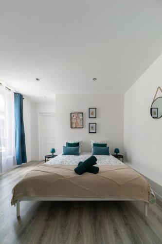 une chambre blanche avec un grand lit avec des oreillers bleus dans l'établissement Résidence Le Celest - Appartements climatisés - Centre ville, à Vichy