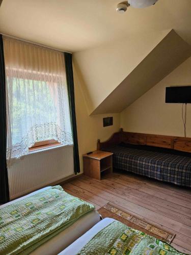 a bedroom with two beds and a window at Panzio Anett in Pietroasa