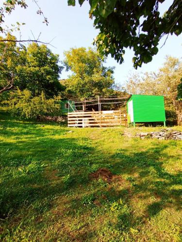 a green barn and a wooden fence in a field at Guest house VL in Alaverdi