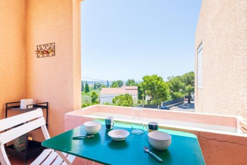 une table verte avec des bols et des verres sur un balcon dans l'établissement Appartement Vistamare - Welkeys, à Bandol