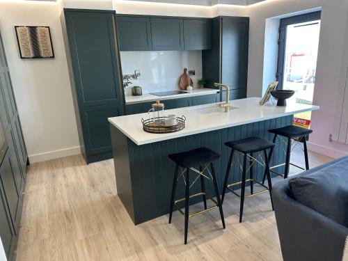 a kitchen with green cabinets and bar stools at Ocean Breeze Apartment in Portrush