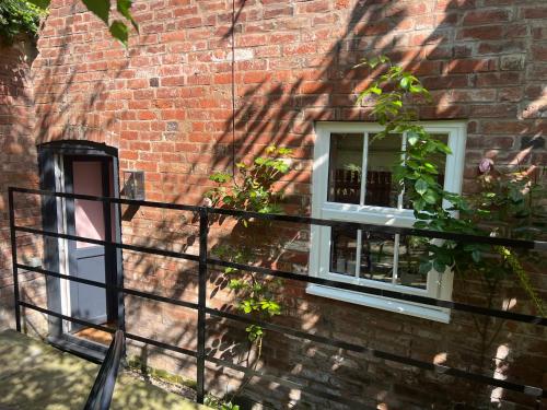 un edificio de ladrillo con dos ventanas y una valla en The Gardener's Cottage, en Leominster