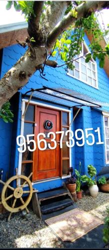 a blue house with a wooden door and a wheel at CABAÑA 325 centro de QUELLON in Quellón