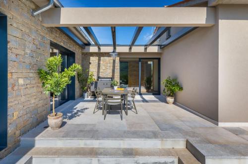 a patio with a table and chairs and a brick wall at Villa Horto in Livade