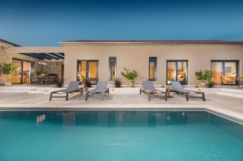 a house with a swimming pool with chairs and a patio at Villa Horto in Livade