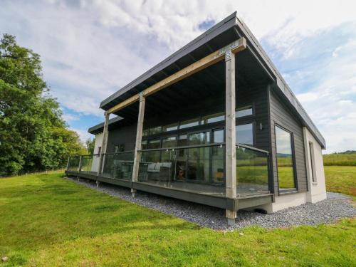 a house with large windows on a grass field at 6 Strathtay Lodges in Aberfeldy