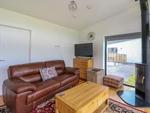 a living room with a leather couch and a fireplace at 6 Strathtay Lodges in Aberfeldy