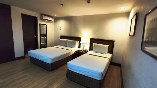 a hotel room with two beds with white sheets at Rajah Park Hotel by Hiverooms in Cebu City