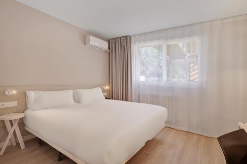 a bedroom with a large white bed and a window at B&B HOTEL Oviedo in Viella
