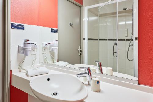 a bathroom with a white sink and a mirror at Ace Hôtel Caen Nord Mémorial in Caen