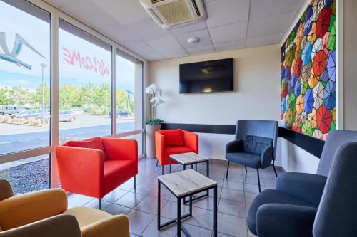 a waiting room with colorful chairs and a window at Ace Hôtel Caen Nord Mémorial in Caen