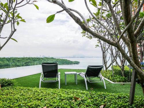 two chairs and a table on a lawn with a lake at Comfort 3 Bedroom Urban Suite by Uptrend Home Management in Jelutong