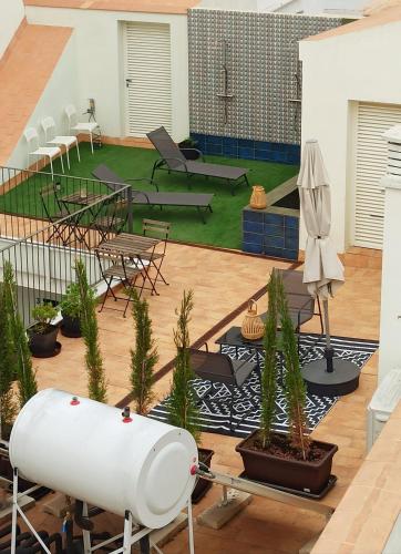 a patio with tables and chairs and a lawn with plants at Apartamentos La Higuera by VGH in Jerez de la Frontera