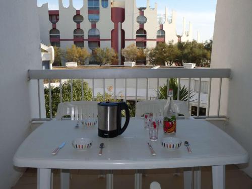 - une table blanche sur un balcon avec une bouteille de vin dans l'établissement Studio cabine proche plage, parking privé - FR-1-328-143, à La Grande Motte