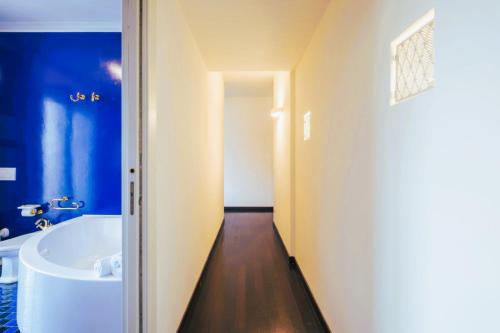 a bathroom with a white tub and a blue wall at Elegant Penthouse With A View Of The Two Towers And Piazza Maggiore in Bologna