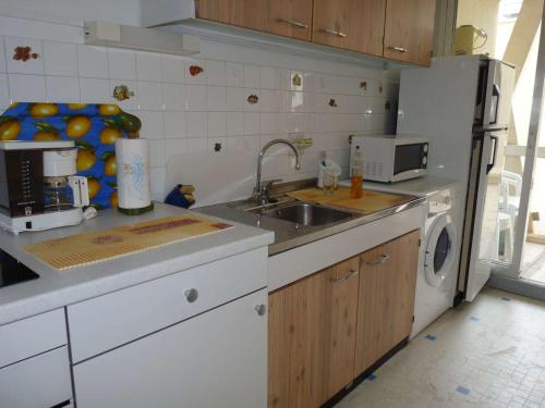 une cuisine avec un évier et un réfrigérateur dans l'établissement Studio avec Loggia, Terrasse & Parking Privé en Centre-Ville, Proche Plage - FR-1-328-99, à La Grande Motte