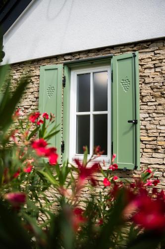 a window with green shutters on a brick building with flowers at Római Home in Hévíz