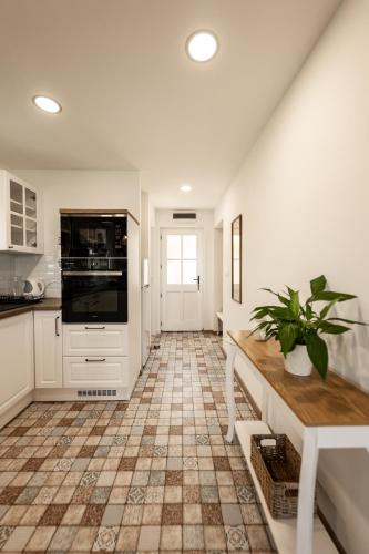 a kitchen with white cabinets and a tile floor at Római Home in Hévíz