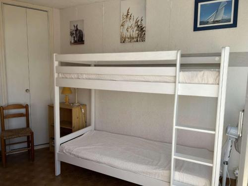 - une chambre avec 2 lits superposés et une chaise dans l'établissement Appartement 2 pièces avec climatisation, 2 terrasses et accès direct au port - Le Grau-du-Roi - FR-1-250-96, au Grau-du-Roi