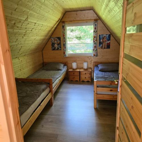 two beds in a small room with a window at Borówkowa Agroturystyka Nad Morzem in Darłowo