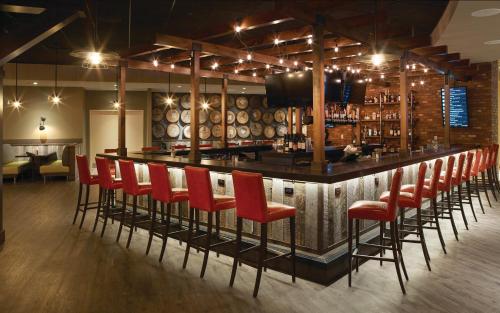 a bar with red chairs in a room with wine barrels at Oxford Casino Hotel in Oxford