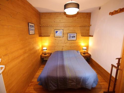 une chambre avec un lit dans une pièce aux murs en bois dans l'établissement Appartement cosy aux Saisies, 2 pièces alcôve, proche des pistes - 6 pers. - FR-1-594-199, à Hauteluce