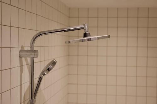 une douche avec pommeau de douche dans une salle de bain dans l'établissement Magnifique appartement - Parc des Buttes Chaumont, à Paris