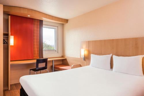 a hotel room with a large bed and a window at ibis Beauvais Aéroport in Beauvais